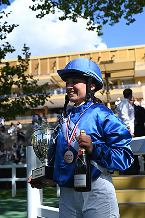 Capucine avec son trophée et une bouteille de champagne dans les mains