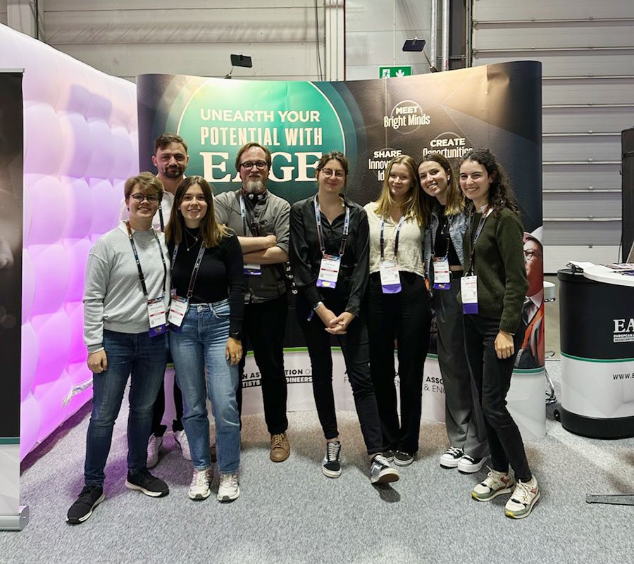 7 étudiants et leur professeur de géologie prennent la pose devant un fond de stand au congrès de l'EAGE