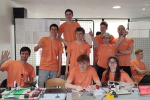 groupe d'étudiants vêtus d'un t-shirt orange posant derrière leur projet