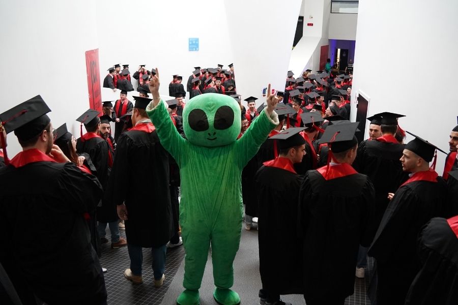 La mascotte d'UniLaSalle Amiens "Alien" (un extraterrestre tout vert) lève les bras au milieu des 160 diplômés d'UniLaSalle Amiens, en tenue d'apparat à l'américaine (toge noire, écharpe rouge et chapeau de diplômé noir